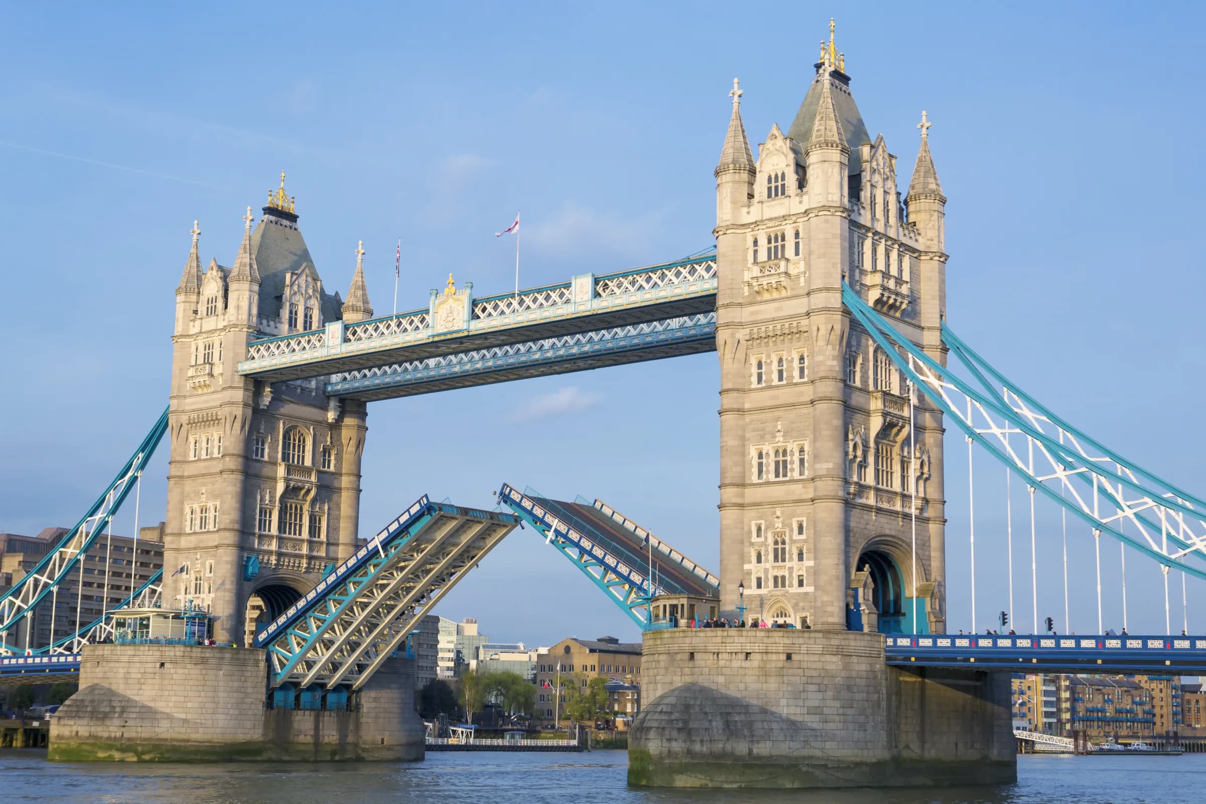 Tower Bridge in London with its road raised, under a clear blue sky