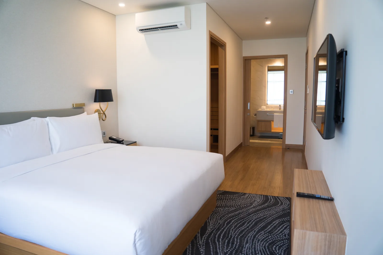 A modern three-star hotel double room with white bedding and an en-suite bathroom